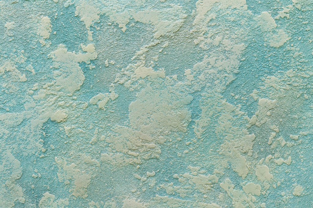 Close-up of turquoise and cream textured wall with a weathered, stucco-like finish.