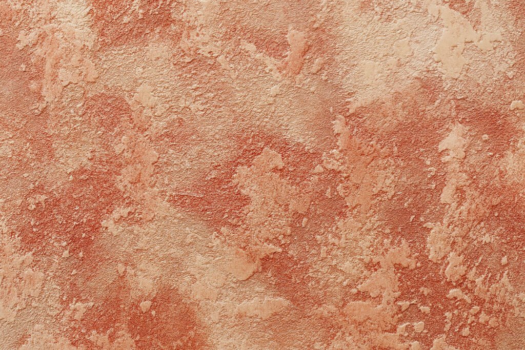 Close-up of rustic orange textured wall with an uneven, stucco-like finish.