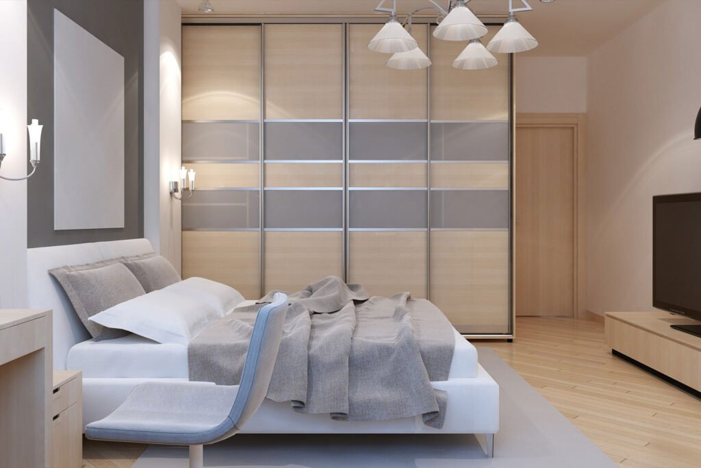 Modern floor-to-ceiling beige wardrobe with sliding doors, featuring horizontal and vertical silver accents, seamlessly integrated into a contemporary bedroom with minimalist decor.
